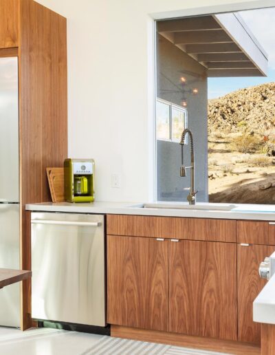 Modern kitchen interior with clean lines, wooden cabinetry, and a desert view through the window.