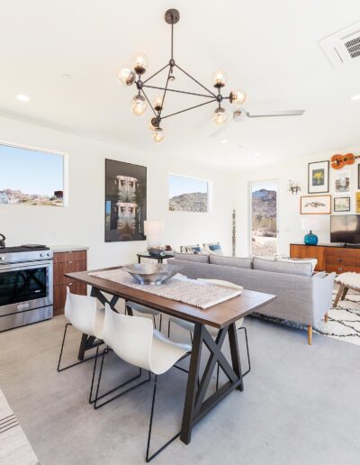 Bright and modern dining-living room combo with a mid-century design influence, featuring clean lines, minimal decor, and large windows with desert views.