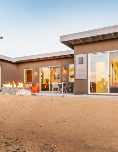 Modern desert home with an outdoor fire pit at dusk.