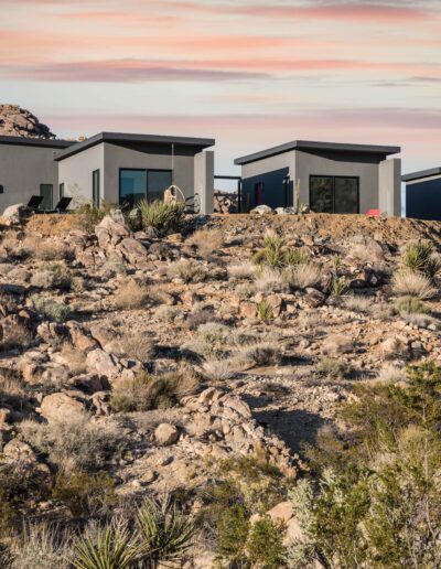 Modern houses nestled among rocky desert terrain at dusk.