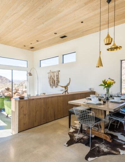 Bright and modern dining room with natural stone accent wall, wood ceiling, and contemporary decor.