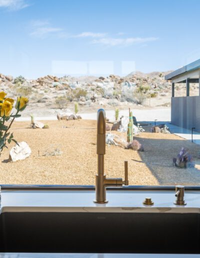 Modern kitchen with a view of a desert landscape through large windows.