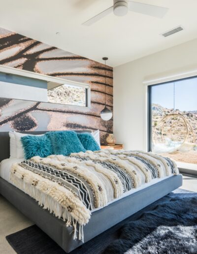 A modern bedroom with a desert view, featuring an expansive wall mural, contemporary furniture, and vibrant blue accents.