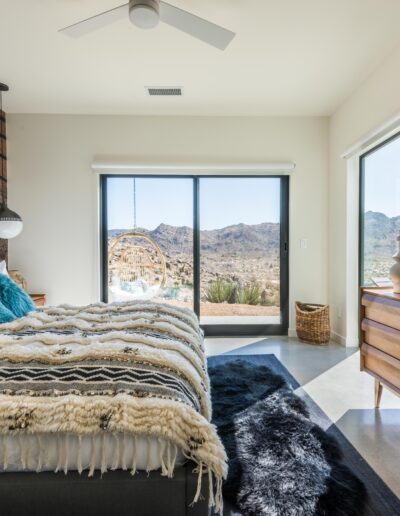 Modern bedroom interior with a large window view of a desert landscape.