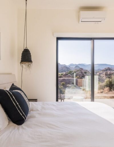 A modern bedroom with large windows offering a view of a mountainous landscape.