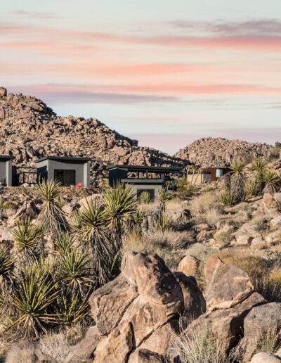 Modern house nestled among rocky desert landscape at twilight.