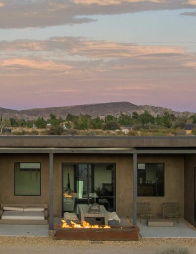 Modern desert home with outdoor seating and fire pit at dusk.