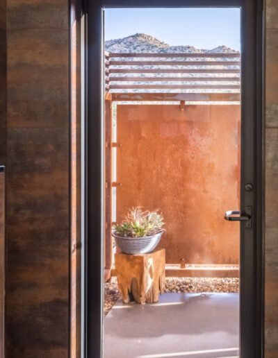 Rustic-style bathroom with an open door leading to an outdoor area with a plant and a view of distant mountains.