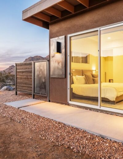 Modern desert accommodation with sliding door entrance at dusk.