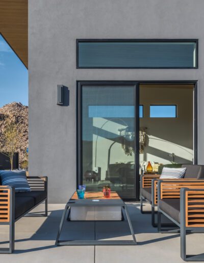 Modern patio furniture arranged in front of a contemporary house with desert landscape in the background.