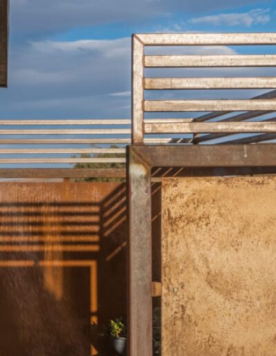 Weathered metal balcony and railing against a backdrop of blue sky and clouds.