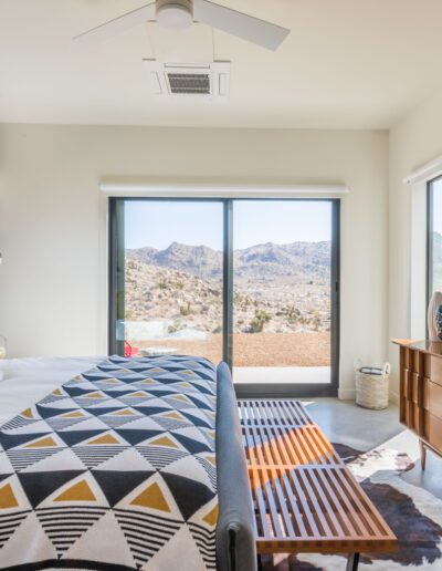 Bright, modern bedroom with a scenic mountain view through large glass doors.