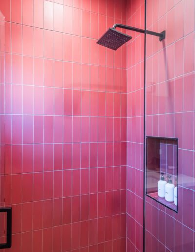 Modern bathroom with a red-tiled walk-in shower and black fixtures.