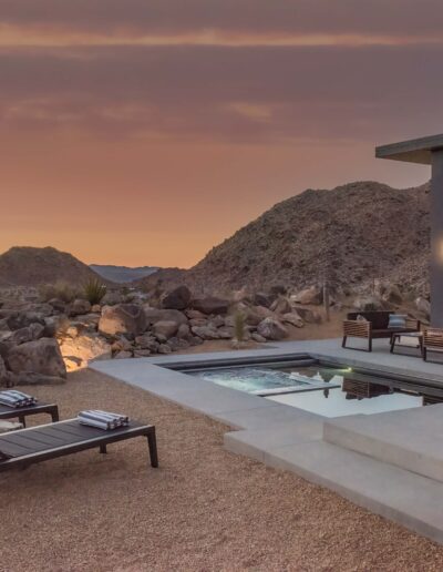 Modern desert home with outdoor seating and pool at dusk.