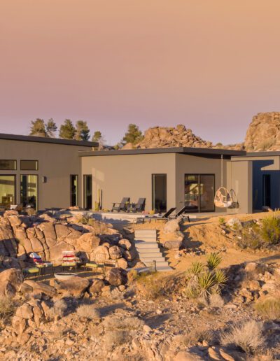 Modern desert home nestled among rocky terrain at dusk.