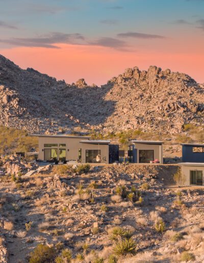 Modern house nestled in a rocky desert landscape at sunset.