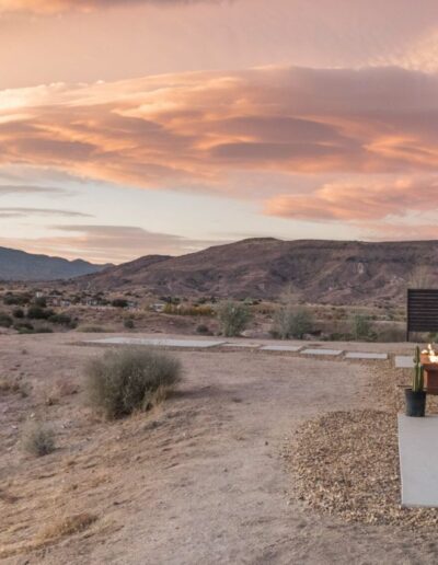 Modern desert home at dusk with expansive views and a dramatic cloud-filled sky.