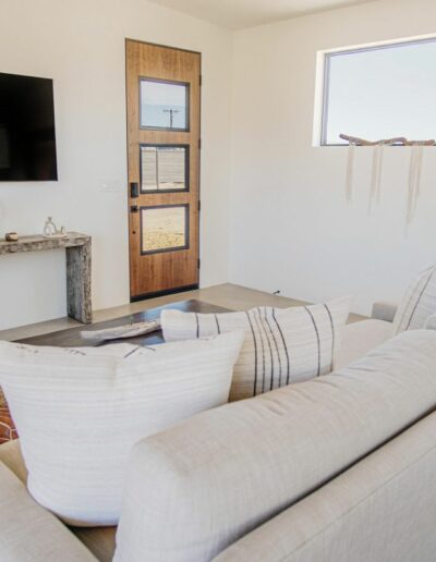 A modern living room with a cream sofa, wall-mounted tv, and wooden door.