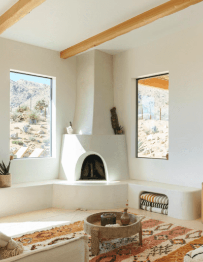 A bright, desert-inspired living space with large windows, a fireplace, and earthy decor.