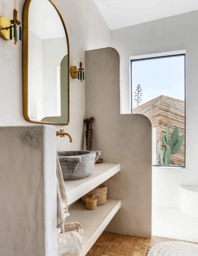 Minimalist bathroom interior with smooth curves, neutral colors, and a view of outdoor greenery through the window.