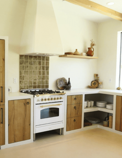 A modern kitchen with wooden cabinetry, a gas stove, white countertops, and a window allowing natural light.