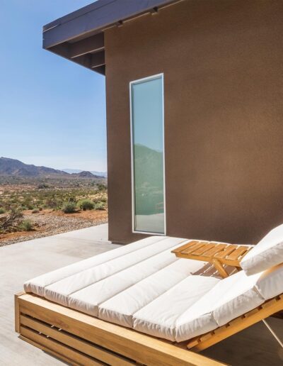 Modern desert home with a tall window and an outdoor lounging area.