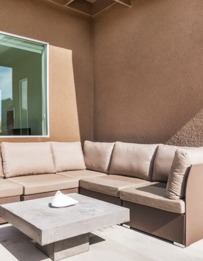 Modern outdoor seating area with a corner sofa and coffee table against a stucco wall.