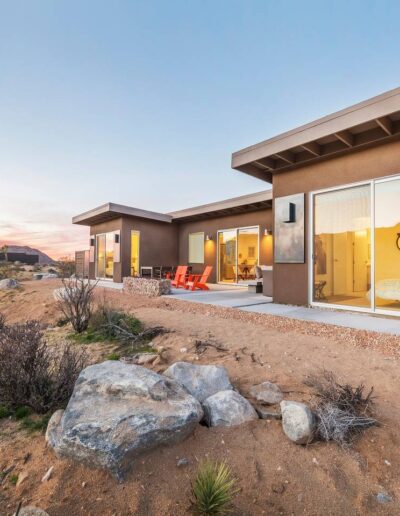 Modern desert home at sunset with outdoor seating area.